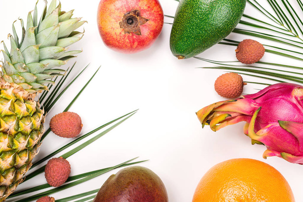 Composición creativa de frutas tropicales de verano. Hojas de palma verde y frutas tropicales sobre fondo blanco
.  - Foto, Imagen