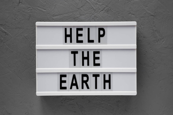 'Help the Earth' words on lightbox over concrete background, top - Photo, Image
