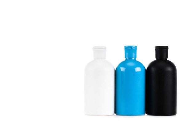 Τρία πολύχρωμα μπουκάλια καλλυντικών με καπάκια απομονώνονται σε λευκό - Φωτογραφία, εικόνα