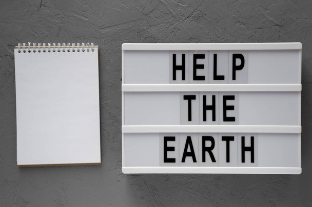 'Help the Earth' words on modern board, blank notepad over concr - Photo, Image