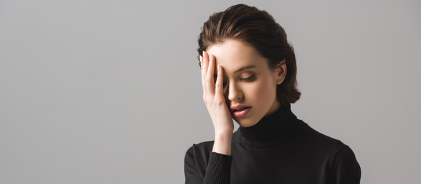 panoramic shot of young woman in black jumper covering eye isolated on grey  - Photo, Image