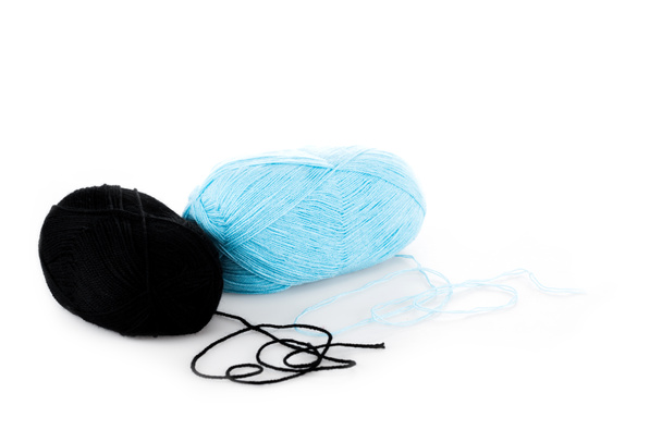Black and blue yarn clews on white surface - Фото, изображение