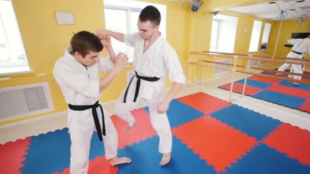 Artes marciales. Dos hombres atléticos entrenando sus habilidades aikido en el estudio. Golpear al oponente en el brazo y tirarlo al suelo
 - Metraje, vídeo
