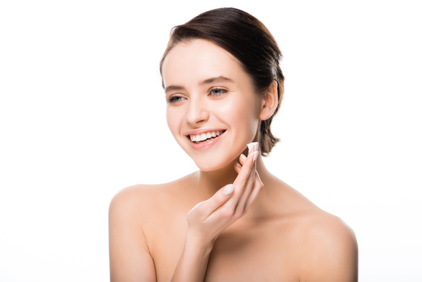 cheerful woman applying face cream and smiling isolated on white  - Фото, изображение
