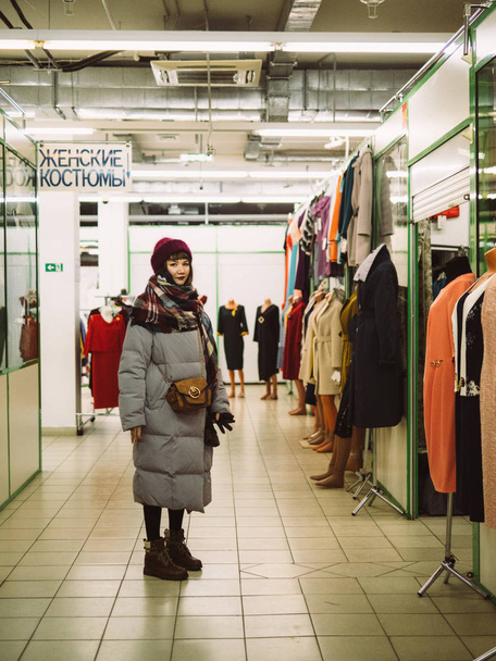 Nuori nainen on selaamassa kiskon vaatteita kauppakeskuksessa
 - Valokuva, kuva