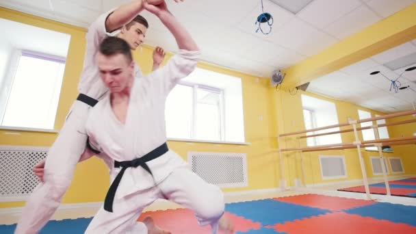 Two athletic men training their aikido skills in the studio. Neutralizing the opponent and throwing him on the floor - Footage, Video