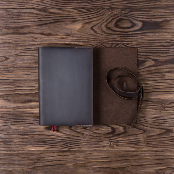 Custodia per notebook in pelle marrone realizzata a mano con notebook su sfondo in legno. Foto stock di accessori business di lusso. Vista dall'alto verso il basso. - Foto, immagini