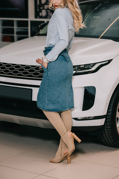 cropped view of blonde girl standing with hand in pocket near white automobile  - Fotografie, Obrázek