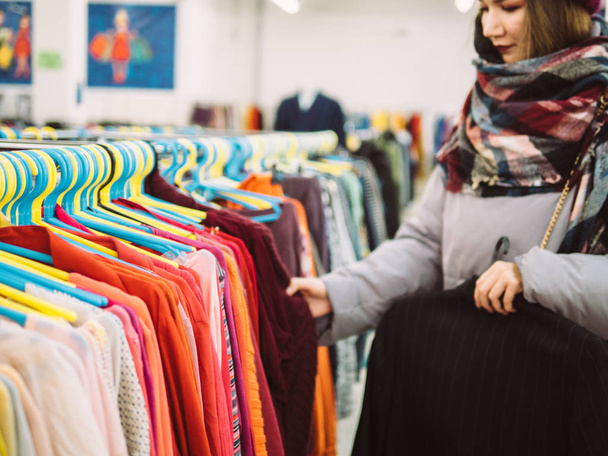 Nuori nainen on selaamassa kiskon vaatteita kauppakeskuksessa
 - Valokuva, kuva