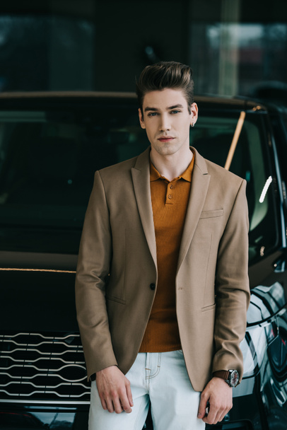 handsome man standing near black automobile and looking at camera  - Photo, Image