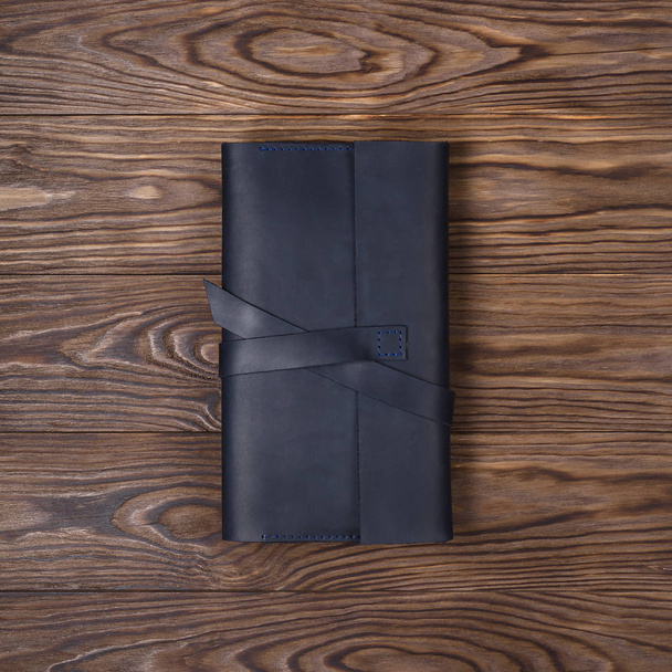 ブラック手作り旅行財布はテクスチャ木製の背景にあります。ダウンビューまで。ビジネスマンのアクセサリーのストックフォト. - 写真・画像