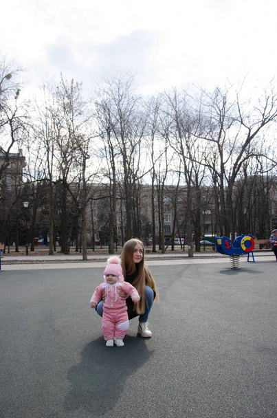 Η μαμά παίζει σε μια φωτεινή παιδική χαρά με ένα μικρό παιδί στο δρόμο, νομάδες, ένα σπίτι κατά τη διάρκεια της ημέρας - Φωτογραφία, εικόνα