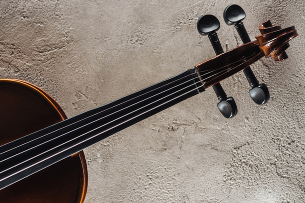 верхний вид струн виолончели на серой текстурированной поверхности
 - Фото, изображение