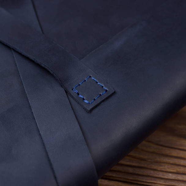 Blue handmade travel wallet lies on textured wooden backgroud closeup. Side view. Stock photo of businessman accessories. - 写真・画像