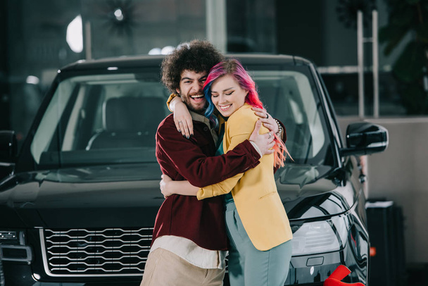 cheerful curly man hugging happy girl with colored hair  - Foto, Bild
