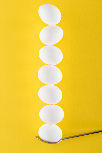 siedem białych jaj kurzych na łyżce na żółtym tle - Zdjęcie, obraz