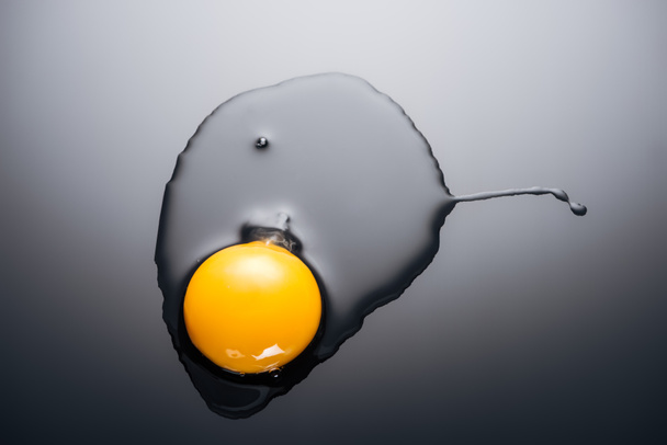 primer plano de huevo crudo machacado con yema y proteína sobre fondo negro
 - Foto, Imagen