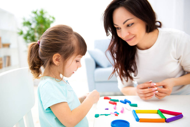 Mom and little daughter sculpt new house of plasticine. Child development and education. Family leisure with a child. Happy childhood - Фото, зображення