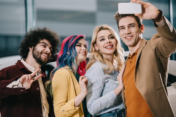 cheerful group of friends smiling while taking selfie on smartphone - Photo, Image