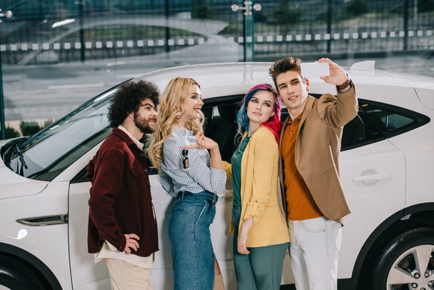 happy group of friends taking selfie on smartphone near white car  - Photo, Image