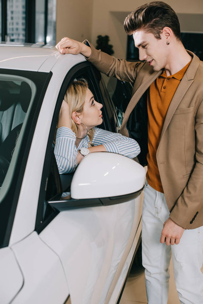 handsome man looking at attractive blonde young woman sitting in car  - Foto, immagini
