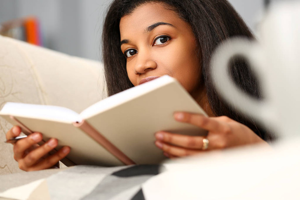 Улыбающаяся чёрная женщина читает сказки дома
 - Фото, изображение