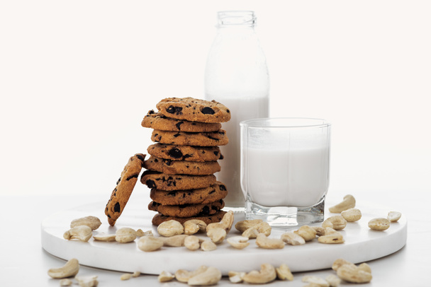 vegan cashew milk in glass and bottle near chocolate cookies isolated on white - Zdjęcie, obraz