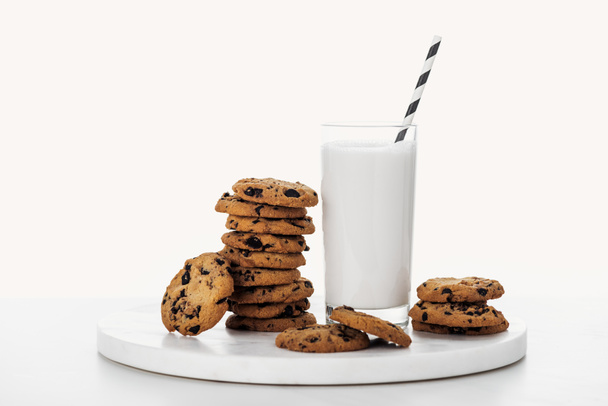 pilha de biscoitos de chocolate saborosos perto de vidro com leite e palha isolada em branco
 - Foto, Imagem