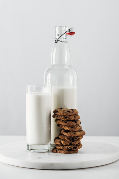 pile of tasty chocolate cookies near bottle and glass with milk isolated on grey - Φωτογραφία, εικόνα