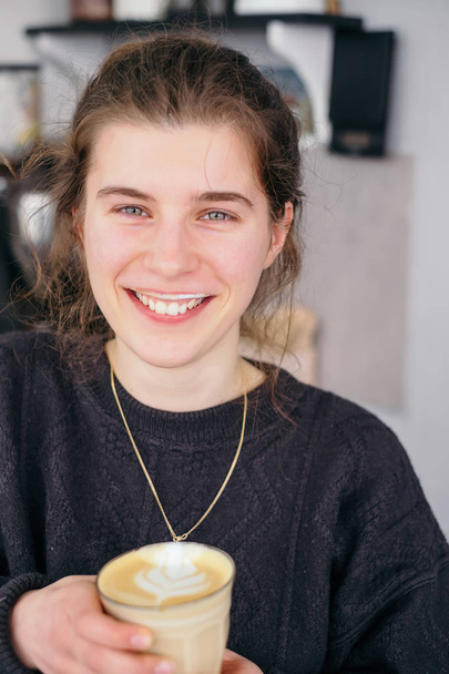 Nuori tyttö hymy ja maku kahvi latte
 - Valokuva, kuva