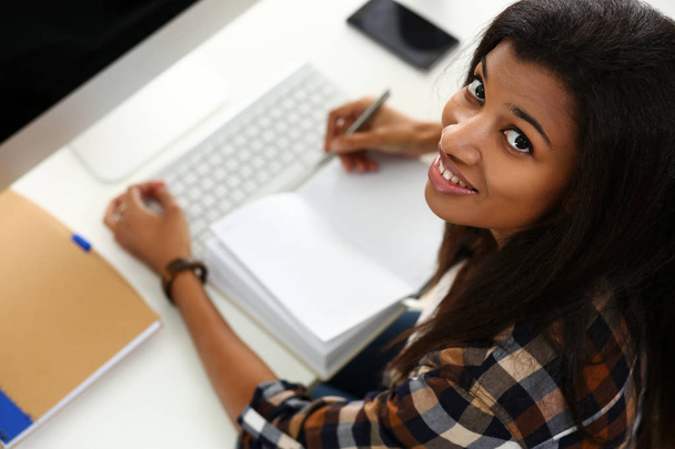 Black smiling woman sitting at workplace working with desktop pc - Fotoğraf, Görsel