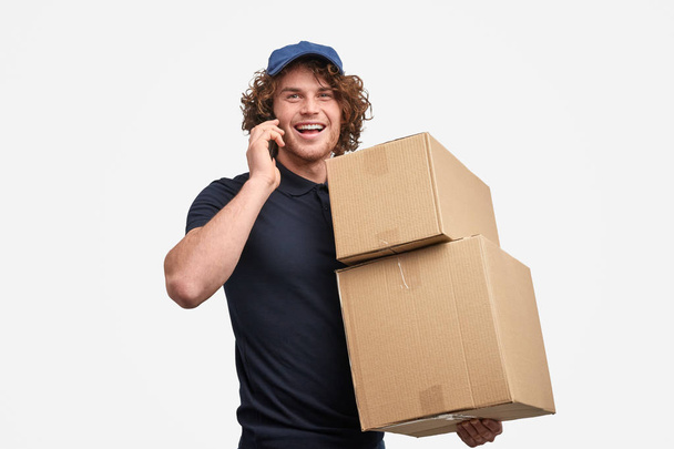 Cheerful courier speaking on phone - Foto, afbeelding
