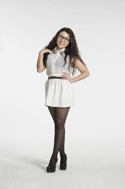 A girl with gorgeous long hair in a white blouse and white skirt emotionally posing. - Fotó, kép