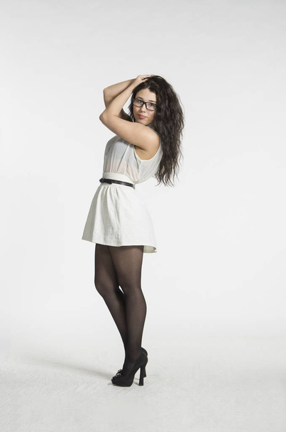 A girl with gorgeous long hair in a white blouse and white skirt emotionally posing. - Zdjęcie, obraz