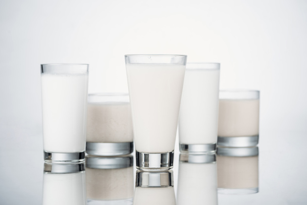 glasses with fresh alternative milk on grey background with reflection - 写真・画像