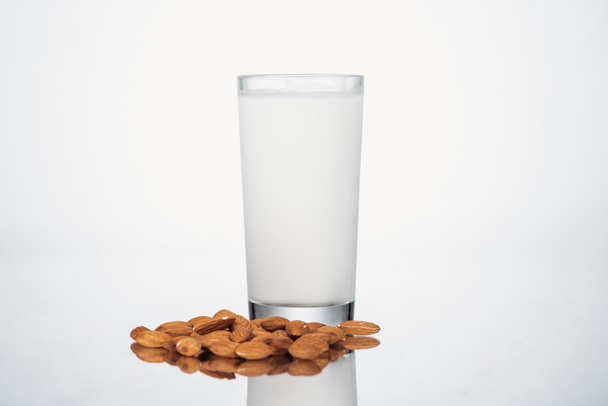 almond vegan milk in glass nuts on grey background - Фото, зображення