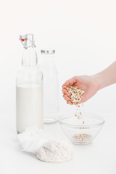 cropped view of woman putting oat flakes in bowl while cooking oat vegan milk - Photo, Image