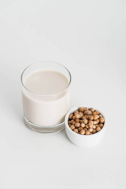 chickpea in bowl near vegan chickpea milk in glass on grey background - Foto, Imagen