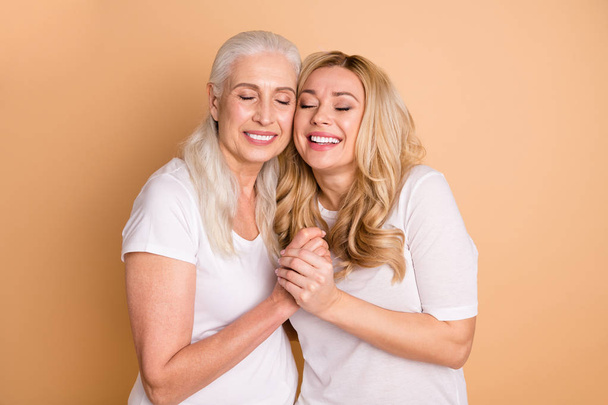 Portrait of nice attractive lovely lovable charming sweet tender gentle kind cheerful dreamy ladies wearing white outfit holding hands bonding isolated over beige pastel background - Φωτογραφία, εικόνα