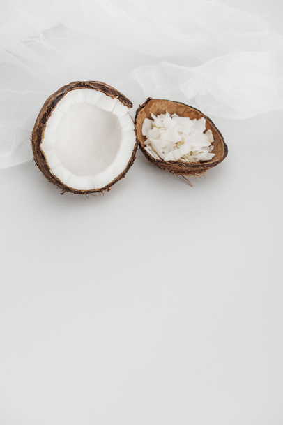 verse kokos helft en chips in de buurt van kaasdoek op grijze achtergrond - Foto, afbeelding