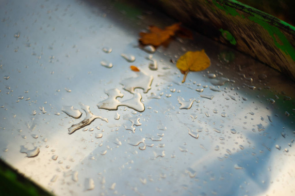 Chuva cai em metal cromado e madeira. A foto mostra uma parte de uma colina infantil - Foto, Imagem