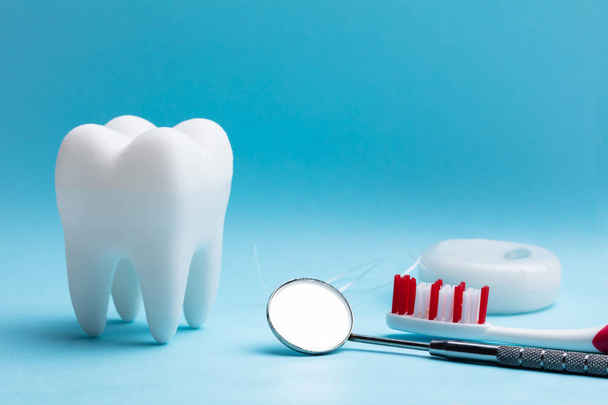 Close-up van witte kunstmatige tand en tandheelkundige apparatuur op blauwe achtergrond - Foto, afbeelding