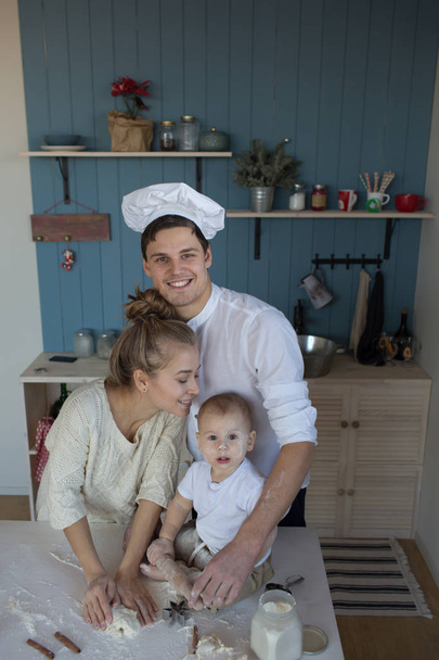 a child with his mother and father in the kitchen rolls out a dough, products from dough, flour, a bakery, bread. Master Class. cook and learn  - Foto, Imagem
