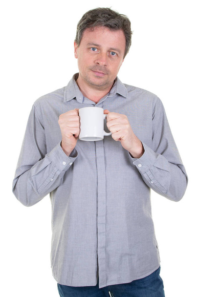 handsome man holding cup with coffee tea with serious face and blank white mug in hand - Photo, Image