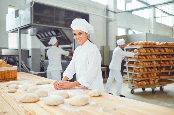 A woman baker smileswith colleagues at a bakery. - Fotó, kép