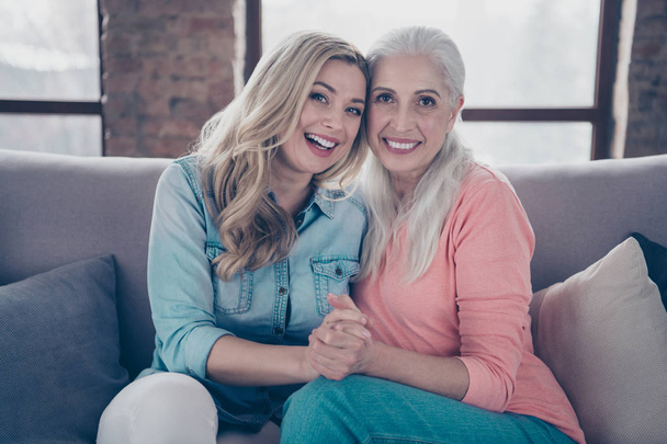 Close up photo two beautiful similarity she her ladies mom granddaughter child granny grandmother hugging hold hands wear casual domestic clothes sit comfy cosy couch divan flat house indoors - Foto, Imagen