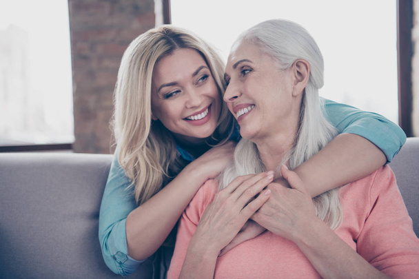 Close up photo two amazing she her ladies mom granddaughter child granny grandmother hugging piggy back look eyes wear casual domestic clothes sit comfy cosy couch divan flat house indoors - Photo, Image