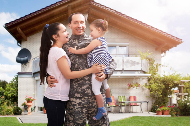 Κοντινό πλάνο ενός ευτυχισμένου στρατιώτη που επανενώθηκε με την οικογένεια έξω από το σπίτι τους. - Φωτογραφία, εικόνα