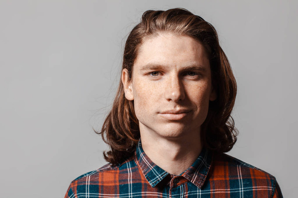 Portrait of a man with long hair and freckles, dressed in a checkered shirt - Foto, imagen