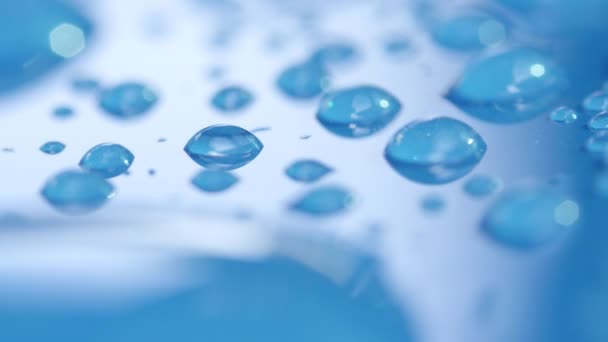DOF, macro, close up: waterdruppels in hoog detail op waterafstotend Aqua Blue Car 's dak. Transparante regendruppels op een blauw oppervlak. Reflecterende bubbels van helder condensatie op glanzende blauwe achtergrond - Video